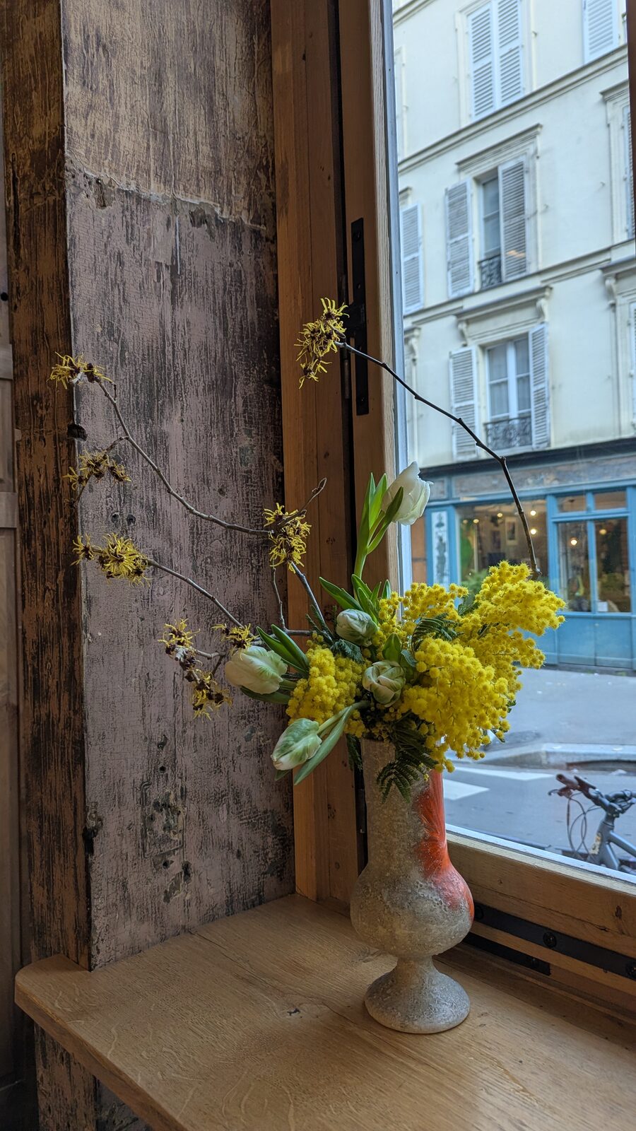Yellow ikebana arrangement beside a window